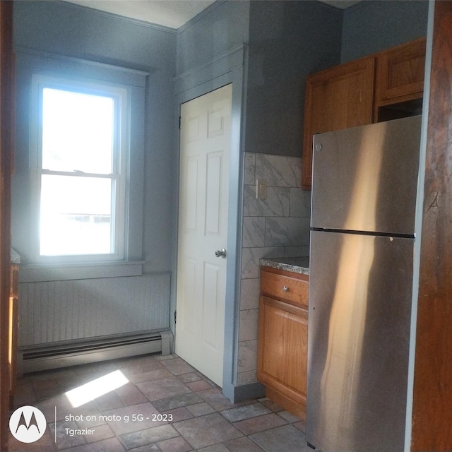 109 Lake Ave, Middletown, NY 10940 - kitchen with freestanding refrigerator, a baseboard heating unit, brown cabinetry, tile walls, and light stone finish floors