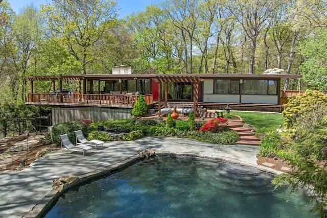 rear view of house with a wooden deck, a patio area, and a pool