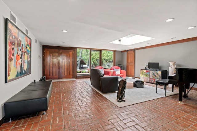 living room with visible vents, brick floor, a skylight, and recessed lighting
