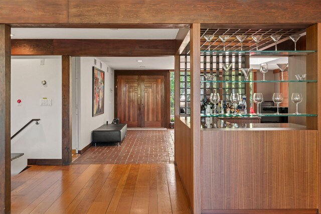 bar with baseboards, wet bar, beam ceiling, and wood-type flooring