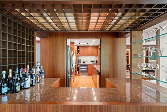wine area with wooden walls, indoor bar, and beverage cooler