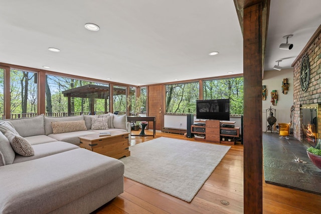 living room with a brick fireplace, wood-type flooring, a baseboard radiator, and recessed lighting
