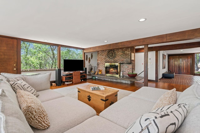 living area with recessed lighting, a brick fireplace, and wood finished floors