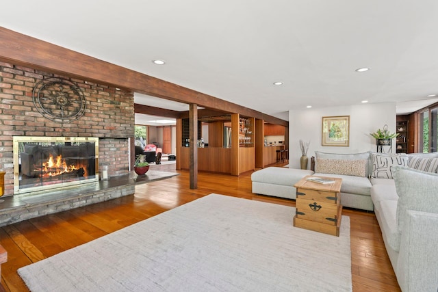 living area featuring wood finished floors, a brick fireplace, and recessed lighting