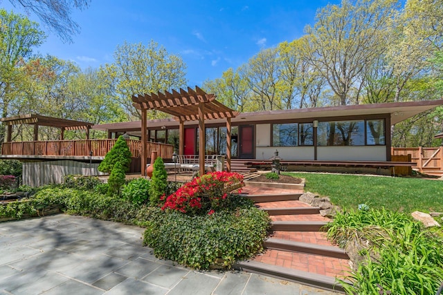 back of property with fence, a pergola, a lawn, and a patio area