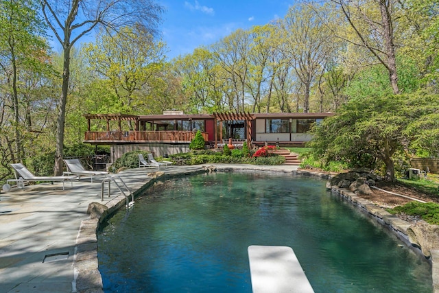 pool with a pergola, a deck, a patio, and a diving board