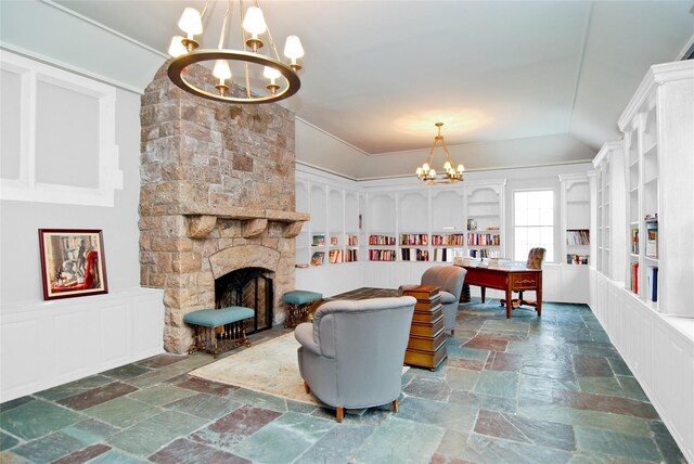 living area featuring an inviting chandelier, a stone fireplace, and stone tile flooring