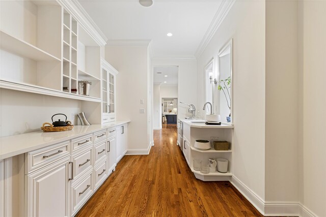 hall featuring baseboards, ornamental molding, wood finished floors, and recessed lighting