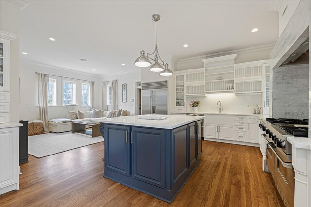 kitchen featuring crown molding, open shelves, a sink, stainless steel built in fridge, and blue cabinets
