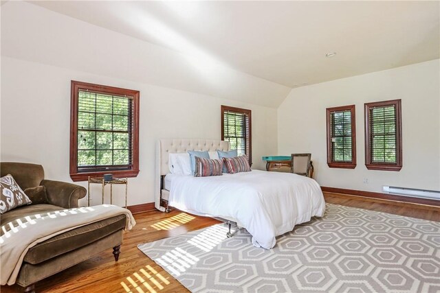 bedroom featuring baseboards, multiple windows, a baseboard heating unit, and lofted ceiling
