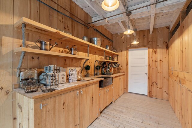 interior space featuring wooden walls, a sink, light wood-style flooring, wooden ceiling, and beamed ceiling