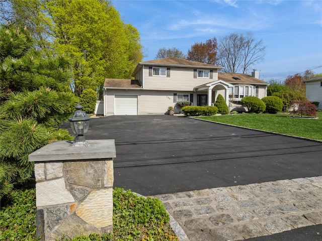 traditional home featuring a front yard, a garage, and driveway