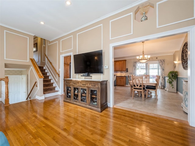living room with crown molding, light wood finished floors, baseboards, and a chandelier