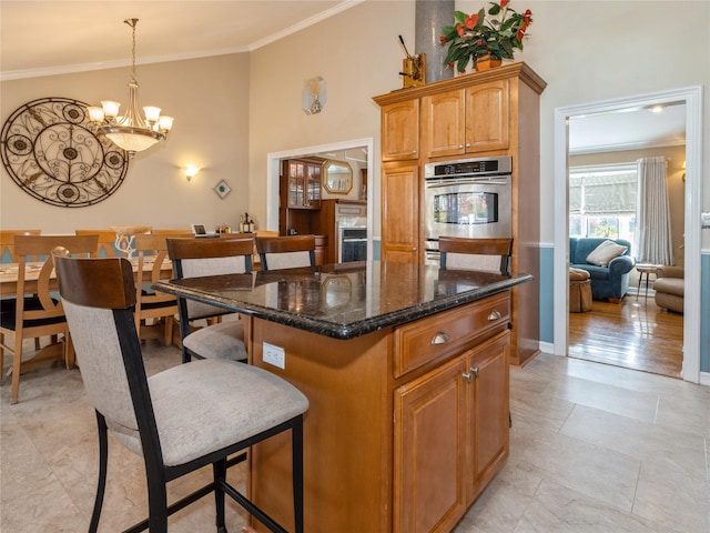kitchen with a chandelier, crown molding, a center island, and dark stone counters