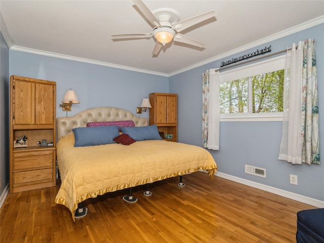 bedroom featuring crown molding, baseboards, visible vents, and wood finished floors