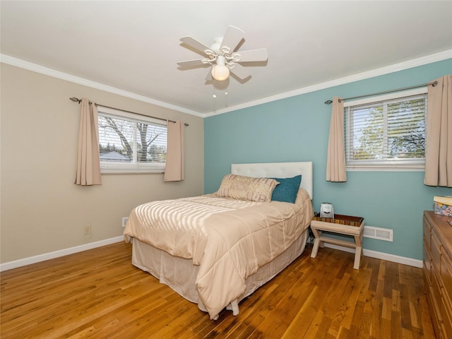 bedroom with baseboards, ornamental molding, ceiling fan, visible vents, and wood finished floors