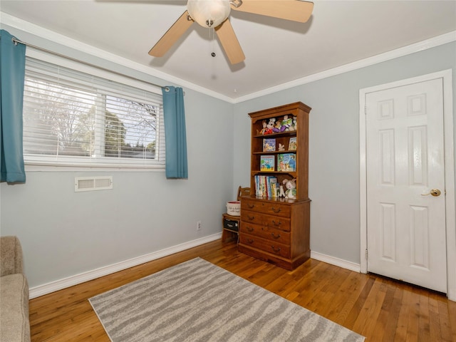 interior space with baseboards, ceiling fan, visible vents, crown molding, and wood finished floors