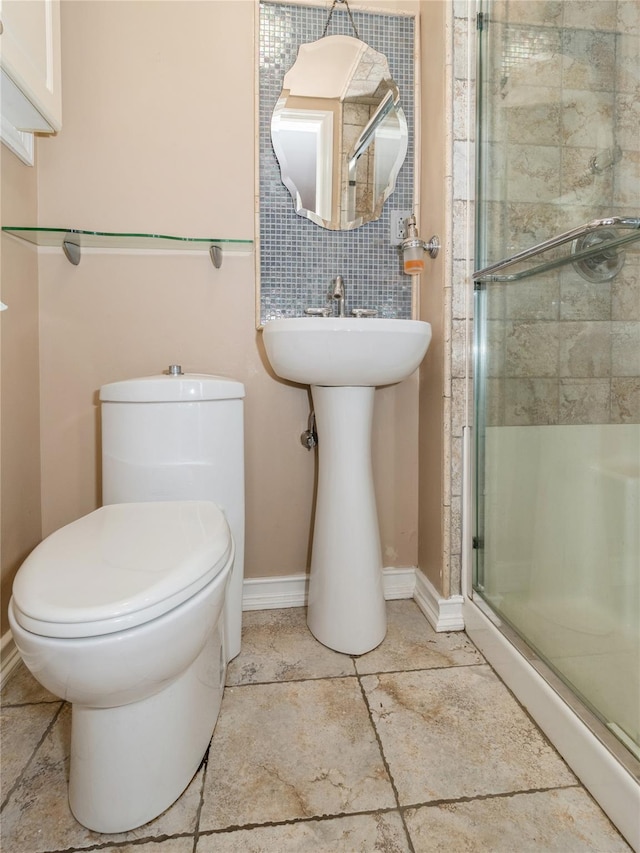 full bathroom featuring a shower stall, baseboards, and toilet