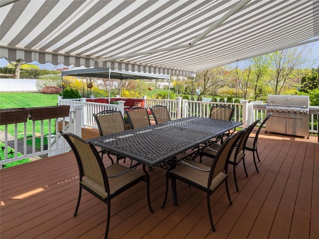 deck featuring a lawn, area for grilling, outdoor dining area, and fence