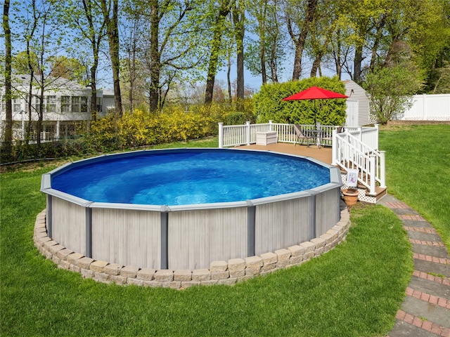 outdoor pool with a yard, a deck, and fence