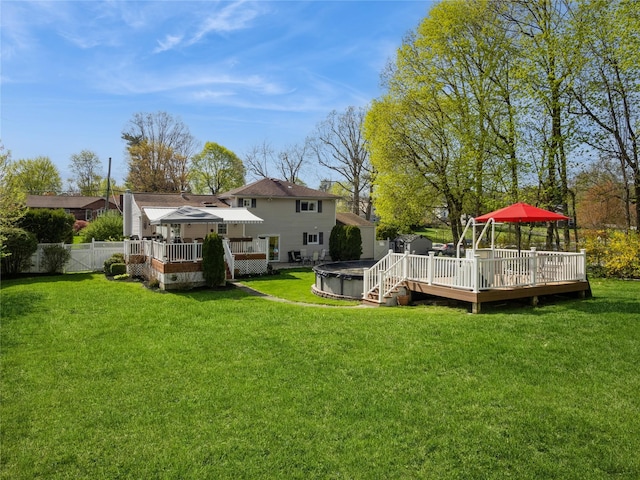 view of yard with a deck, a jacuzzi, and fence