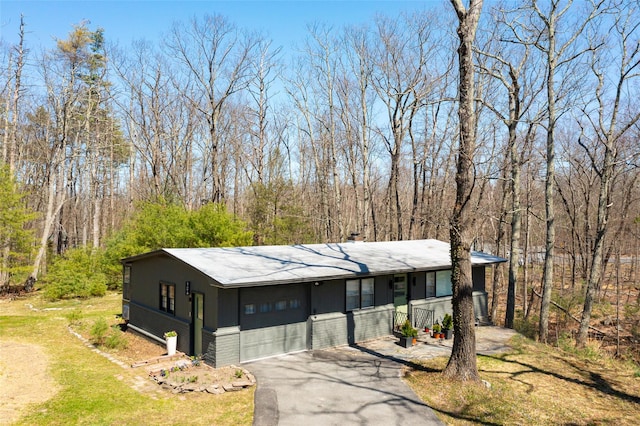 ranch-style home featuring an attached garage and aphalt driveway