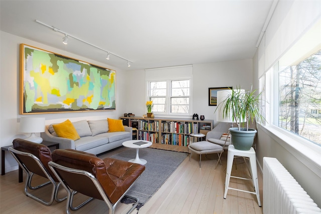 living area with radiator heating unit, hardwood / wood-style flooring, and rail lighting