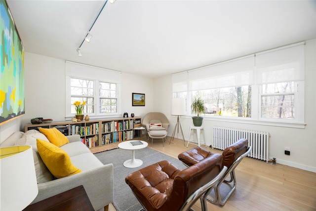 living room with track lighting, radiator, baseboards, and wood finished floors