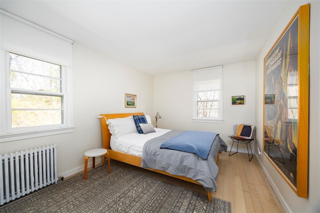 bedroom with radiator heating unit, hardwood / wood-style flooring, and baseboards