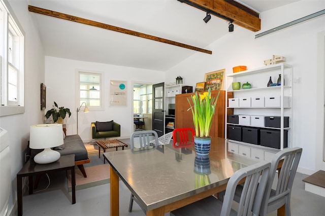 dining area featuring lofted ceiling with beams and concrete floors