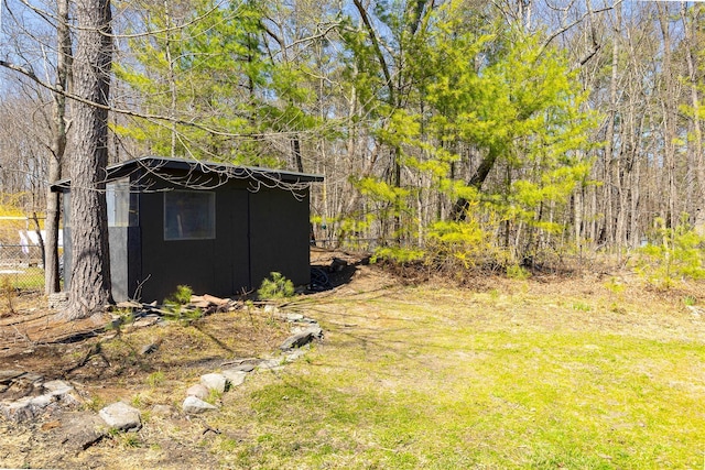 view of yard featuring a forest view, an outdoor structure, and fence