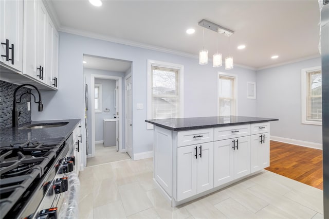 kitchen with stainless steel range with gas cooktop, a sink, ornamental molding, and a healthy amount of sunlight