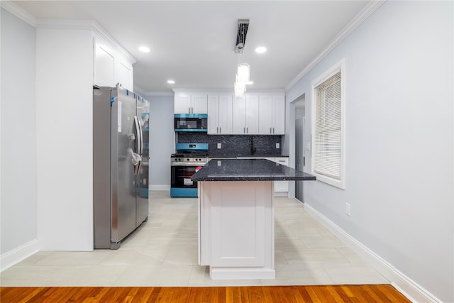 kitchen with backsplash, ornamental molding, a center island, appliances with stainless steel finishes, and white cabinetry