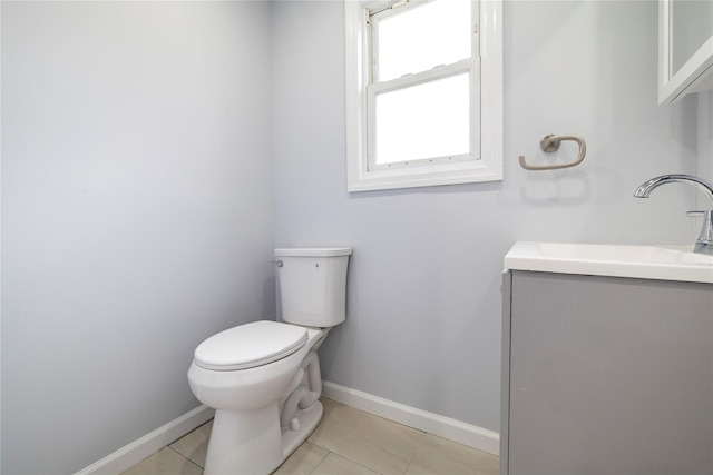 half bath featuring vanity, toilet, baseboards, and tile patterned floors