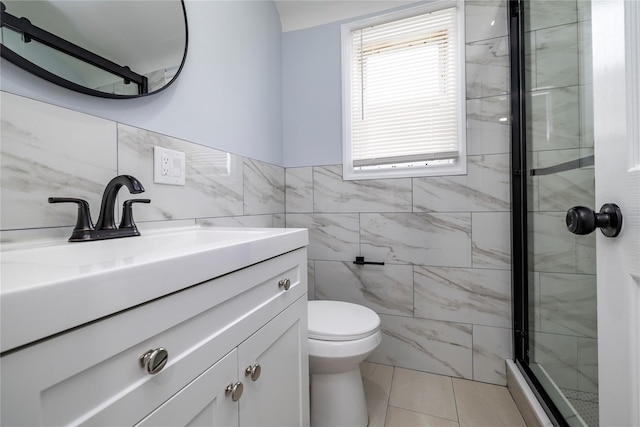full bath featuring a shower stall, tile patterned floors, toilet, vanity, and tile walls