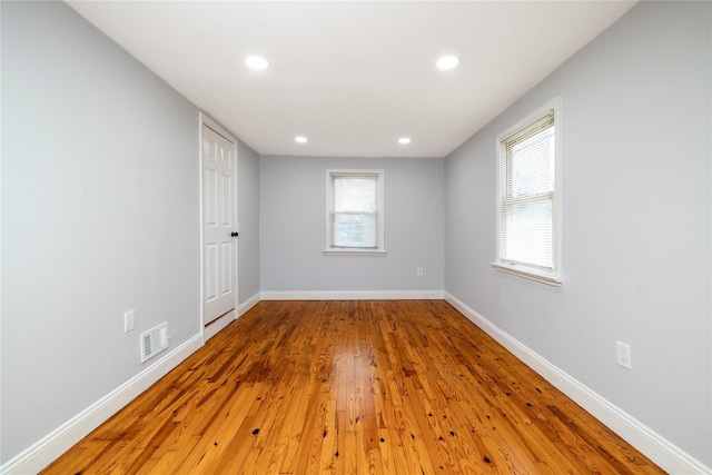 empty room with recessed lighting, wood finished floors, visible vents, and baseboards