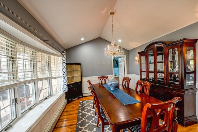 dining room featuring a notable chandelier, a wainscoted wall, wood finished floors, and lofted ceiling