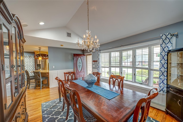 dining space featuring visible vents, wainscoting, vaulted ceiling, light wood-type flooring, and a notable chandelier