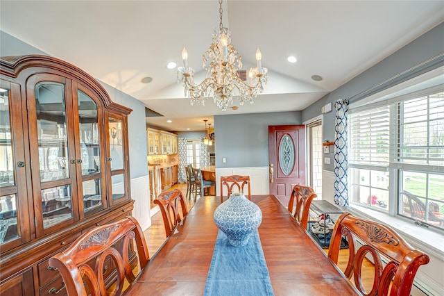 dining area with wainscoting, visible vents, a chandelier, lofted ceiling, and a decorative wall
