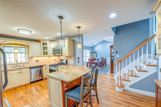 kitchen with glass insert cabinets, stainless steel appliances, light wood-type flooring, a peninsula, and a kitchen breakfast bar