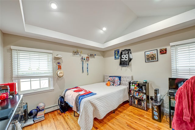 bedroom with a baseboard heating unit, vaulted ceiling, and wood finished floors