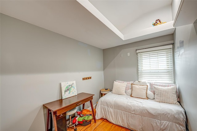 bedroom with light wood-style flooring, vaulted ceiling, and baseboards