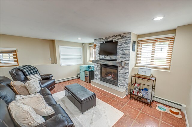 living room featuring a stone fireplace, tile patterned flooring, a baseboard heating unit, and baseboards