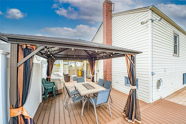 deck with outdoor dining area, a gazebo, and fence