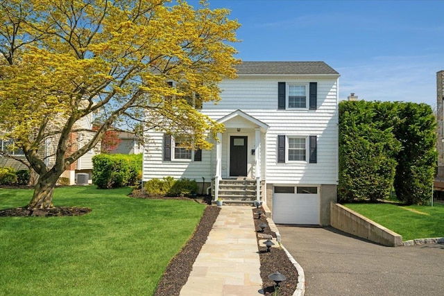 colonial-style house with driveway, a front yard, and a garage
