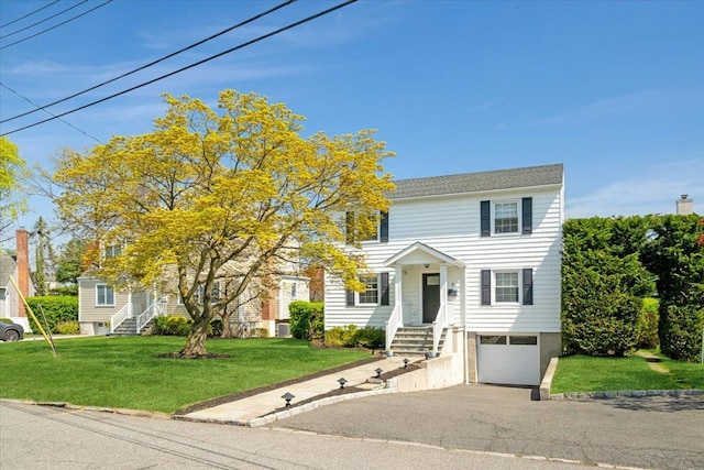 colonial home with a front lawn, an attached garage, and aphalt driveway