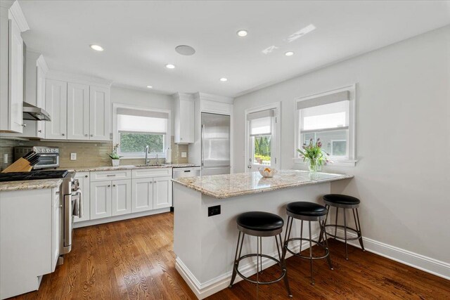 kitchen with a sink, white cabinets, appliances with stainless steel finishes, and a healthy amount of sunlight