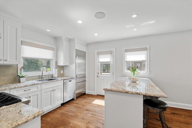 kitchen featuring a sink, a kitchen bar, dishwasher, and baseboards