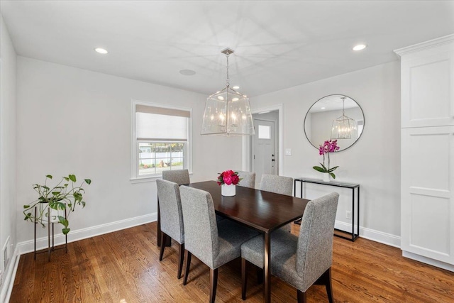 dining space featuring wood finished floors, a notable chandelier, and baseboards