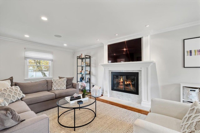 living room with recessed lighting, wood finished floors, crown molding, and a fireplace
